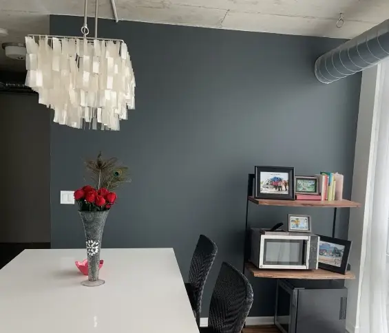 Modern dining area with gray wall, pendant light, and floating shelves