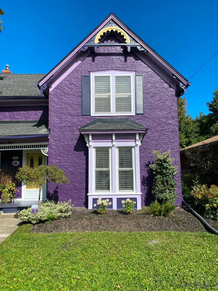 Purple Victorian style house exterior with decorative trim and front garden