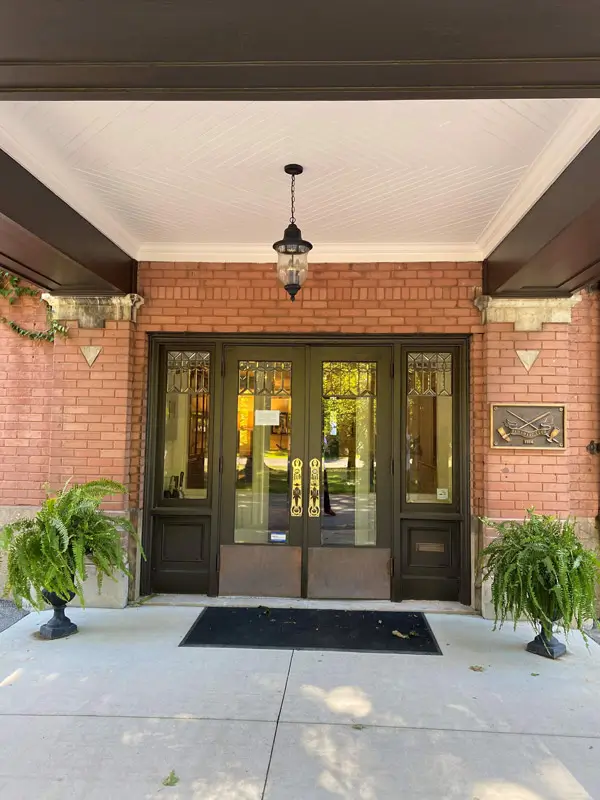 Brick building entrance with glass double doors, hanging lantern, and potted ferns