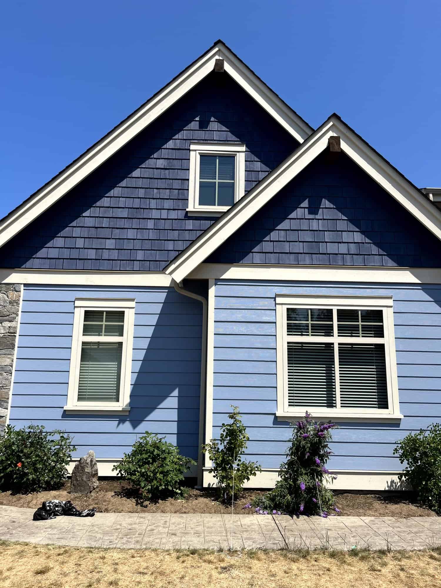 Blue house exterior with white trim and front garden landscaping