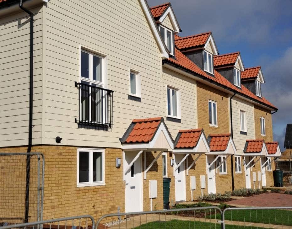 Row of modern townhouses with beige siding and red tiled roofs