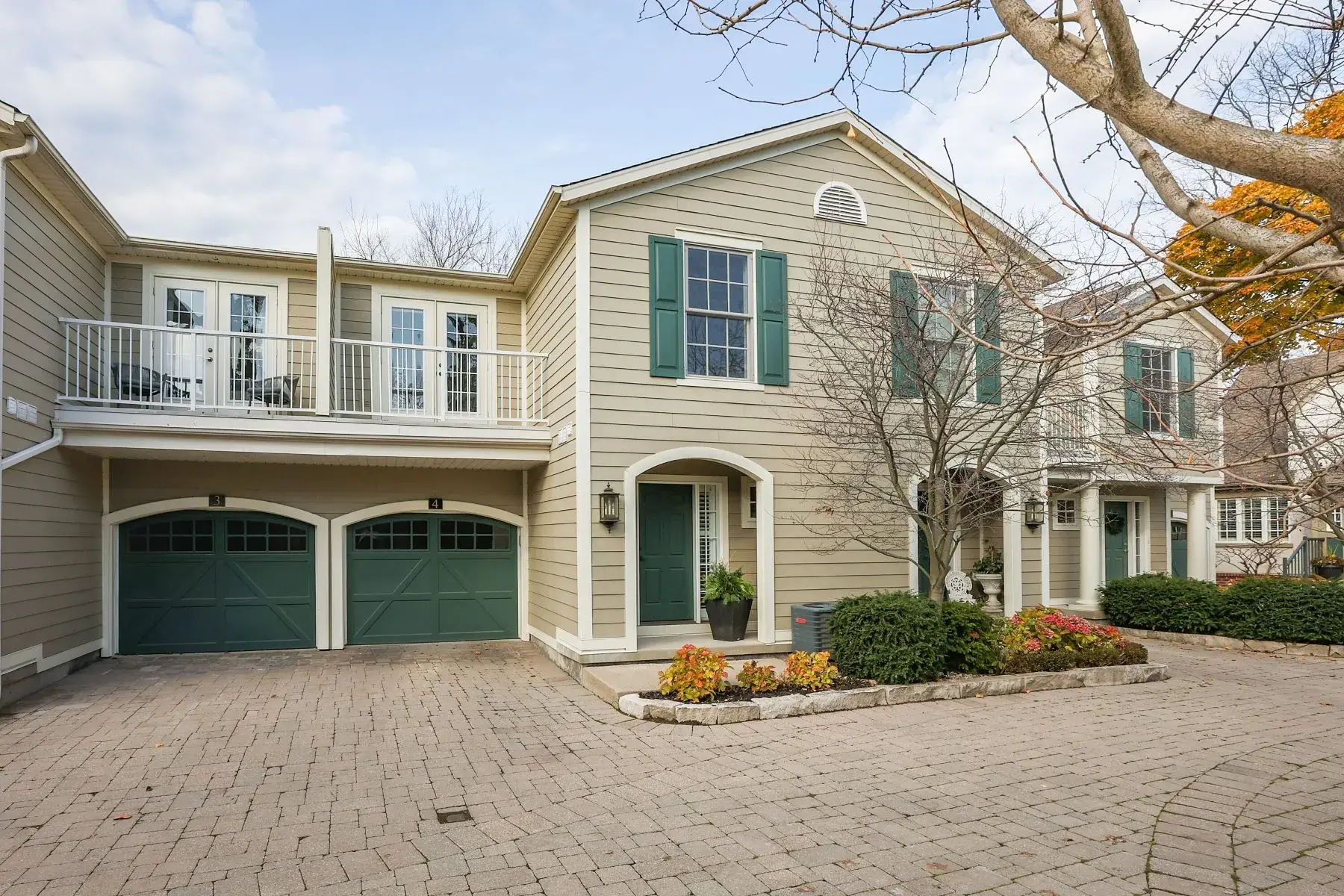 Beige townhouse exterior with green garage doors and small front courtyard