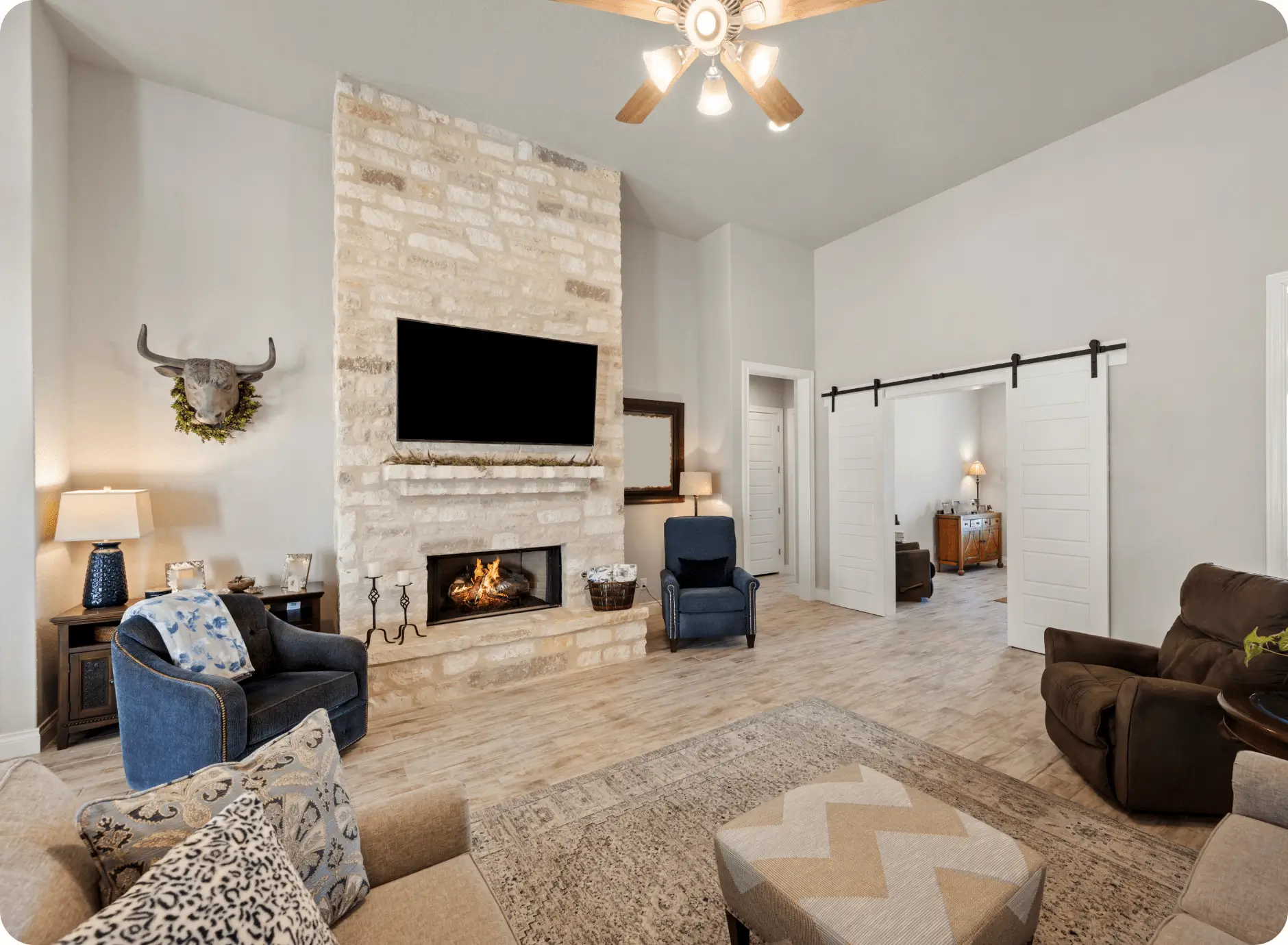 Bright living room with stone fireplace, mounted TV, and cozy seating