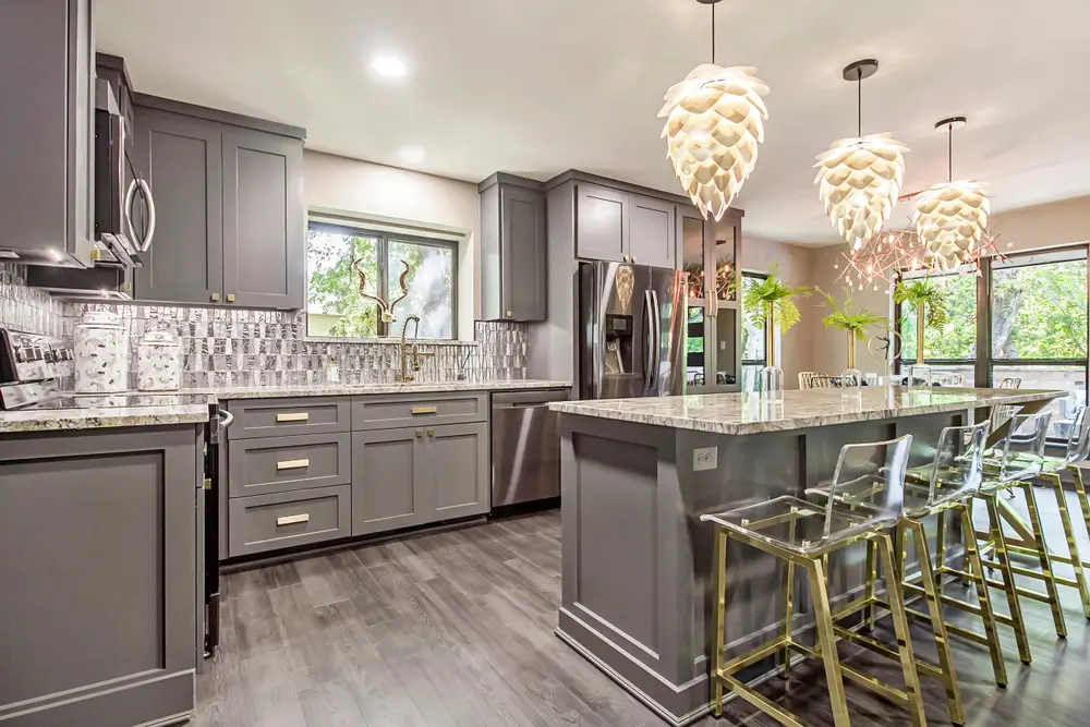 Modern gray kitchen with large island, pendant lighting, and stainless appliances